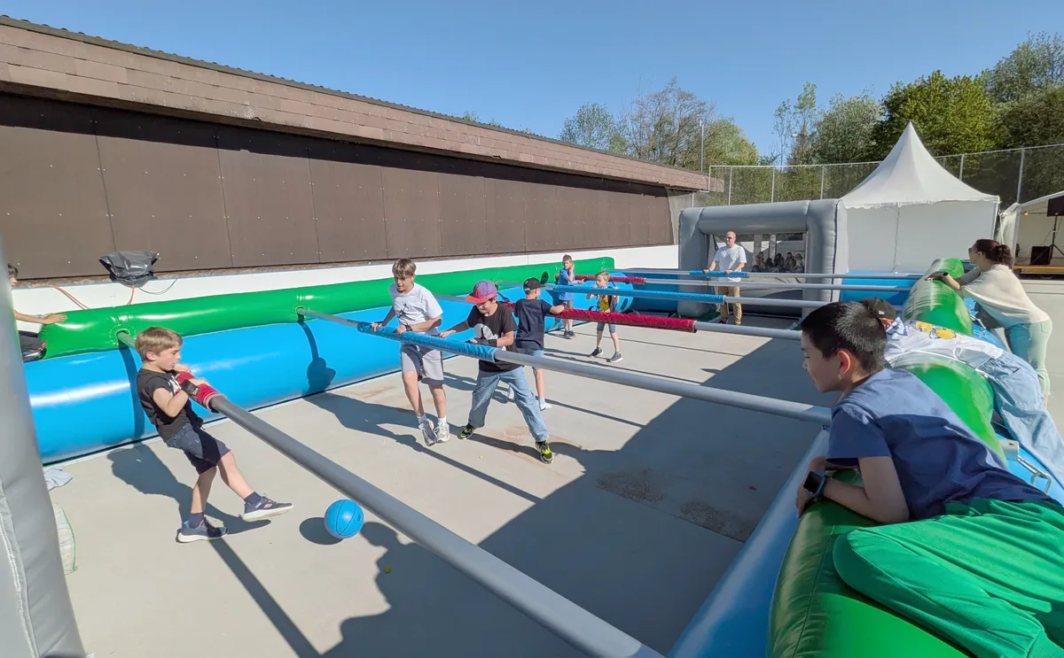 Kinder spielen in einem aufblasbaren Töggelikasten.